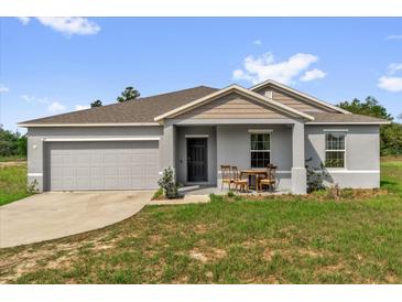 Charming single-story home with a gray exterior, inviting front porch, and well-manicured lawn at 123 Zinnia W Ln, Poinciana, FL 34759