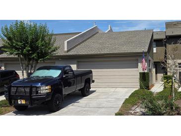 Charming townhome featuring a one-car garage, manicured lawn, and patriotic American flag display at 136 Teriwood Ct, Fern Park, FL 32730
