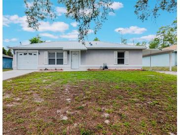Charming single-story home featuring a metal roof, front lawn, one-car garage, and carport at 160 Chestnut Ave, Orange City, FL 32763