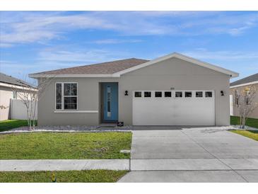 Charming single-story home with a two car garage, manicured lawn and a lovely blue front door at 284 White Heron Way, St Cloud, FL 34772