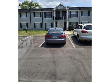 Two-story condo building featuring stairs to upper units, parking spaces, and neutral-toned exterior at 7628 Forest City Rd # 054A/K/A F, Orlando, FL 32810