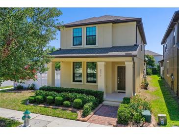 Charming two-story home with a well-manicured lawn, colorful bushes, and a lovely front porch at 8057 John Hancock Dr, Winter Garden, FL 34787