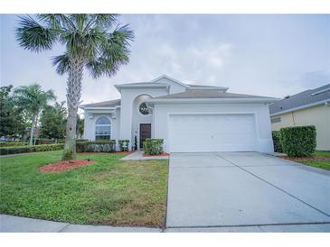 Charming home features a two-car garage, well-maintained landscaping, and a decorative palm tree in the front yard at 8100 Fan Palm Way, Kissimmee, FL 34747