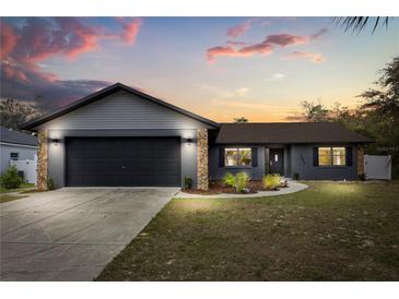 A beautifully renovated single Gathering home featuring a gray exterior, with stone accents and a two-car garage at 15690 Sw 46Th Cir, Ocala, FL 34473