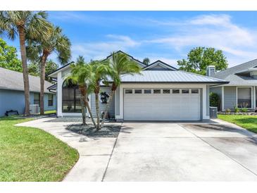 Charming single-Gathering home featuring a metal roof, a two-car garage and lush tropical landscaping at 2391 Piedmont Lakes Blvd, Apopka, FL 32703