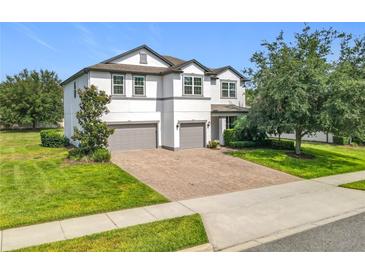 Beautiful two-story home featuring a manicured lawn and a brick-paved driveway, enhancing its curb appeal at 3184 Pinenut Dr, Apopka, FL 32712
