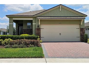 Charming single-Gathering home featuring a two-car garage, brick accents and tidy landscaping at 3371 Yellowtop Loop, Clermont, FL 34714