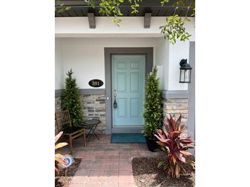 Charming facade featuring a light blue front door, brick accents, and decorative plants, creating a welcoming entrance at 391 Cape Honeysuckle Pl, Sanford, FL 32771