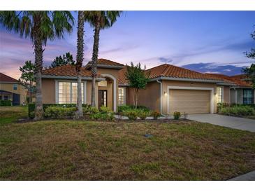 Charming single-story home featuring a tile roof, front-facing garage, and tropical landscaping at 4080 Oaktree Dr, Davenport, FL 33837