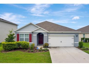 Charming single-story home with a well-manicured lawn, a two-car garage and red shutters at 868 Brooklet Dr, Davenport, FL 33837