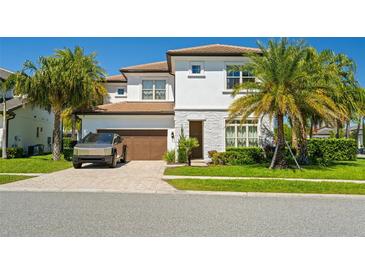 Charming two-story home with a well-manicured lawn and a Tesla Cybertruck parked out front at 10829 Royal Cypress Way, Orlando, FL 32836