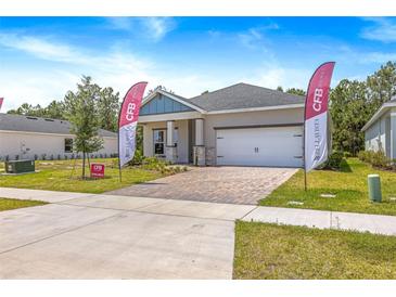Charming single-story home featuring a brick driveway, two-car garage, and landscaped front yard at 1257 Champions Dr, Daytona Beach, FL 32124