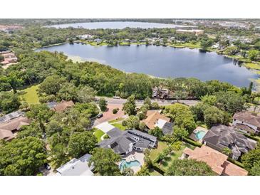 Stunning aerial view of lakeside home, lush greenery, and inviting pool, making it perfect for relaxation at 1327 Bridgeport Dr, Winter Park, FL 32789