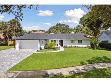 Charming exterior with lush green lawn, brick driveway, and meticulous landscaping at 1327 Bridgeport Dr, Winter Park, FL 32789
