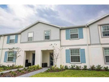 Inviting two-story townhome showcasing a charming exterior with light blue shutters and manicured landscaping at 271 Jetty Way, Davenport, FL 33897