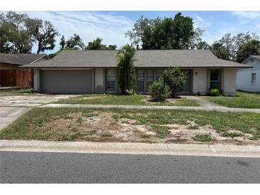 A single-story home with an attached garage and neutral-colored exterior sits on a grassy lot at 5918 Stratton Ln, Orlando, FL 32808