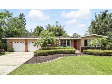 Charming single-story home with a manicured lawn, colorful flower beds, and an attached two-car garage at 619 Byron Rd, Winter Park, FL 32792