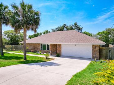 Charming brick home with a manicured lawn, mature palm trees, and a two-car garage at 1233 Gladstone Dr, Deltona, FL 32725