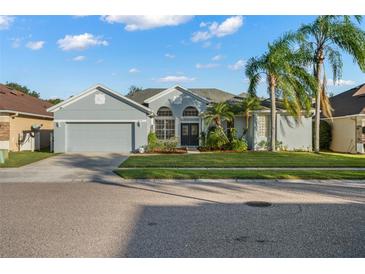 Charming single Gathering home with a manicured front yard, lush landscaping, and gray exterior at 14131 Islamorada Dr, Orlando, FL 32837