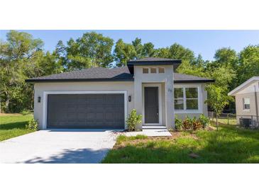 Beautiful single-story home featuring a gray exterior, dark gray garage door, and neatly landscaped front yard at 25 W 7Th St, Apopka, FL 32703