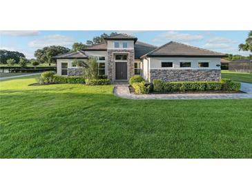Charming single-Gathering home featuring stone accents, a well-manicured lawn, and a tiled roof at 25859 Crossings Bluff Ln, Sorrento, FL 32776