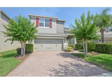 Two-story home with red shutters, two-car garage, brick paver driveway, and neatly landscaped front yard at 5908 Paxton Ct, Apopka, FL 32703