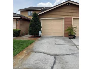 Exterior view of home featuring a two-car garage, brown siding, and landscaped front yard at 707 Carpenters Way # 50, Lakeland, FL 33809