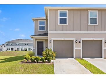 Charming two-story townhome featuring a two-car garage and well-manicured landscaping against a clear blue sky at 1401 Mirabella Cir, Davenport, FL 33897