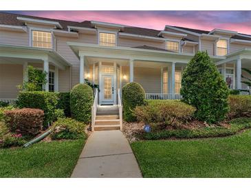 Inviting two-story townhome featuring a charming front porch and beautifully landscaped front yard with manicured bushes at 152 Riggings Way, Clermont, FL 34711