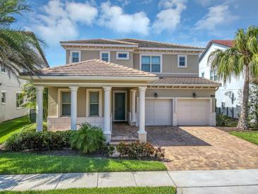 Beautiful two-story home with a two-car garage, classic columns, tile roof, and lush tropical landscaping at 15769 Shorebird Ln, Winter Garden, FL 34787