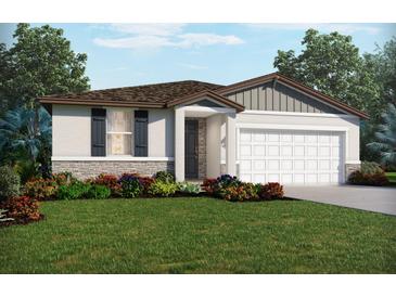 Charming one-story home featuring a two-car garage, stone accents, lush landscaping, and welcoming front entrance at 2089 Rosewood Dr, Bartow, FL 33830