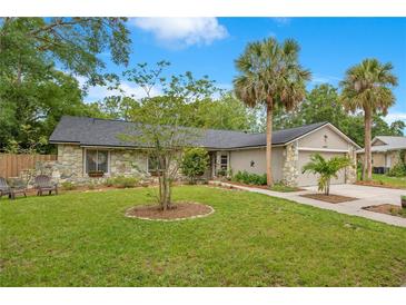 Charming single-story home featuring stone accents, a well-manicured lawn, and lush palm trees at 2901 Autumnwood Trl, Apopka, FL 32703