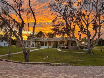 Charming home with pergola and beautiful landscaping, set against a vibrant sunset sky at 775 Bay Dr, New Smyrna Beach, FL 32168