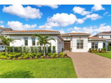 Beautiful single-story home with manicured lawn, lovely landscaping, brick driveway, and tile roof at 13791 Abberwick Dr, Orlando, FL 32832