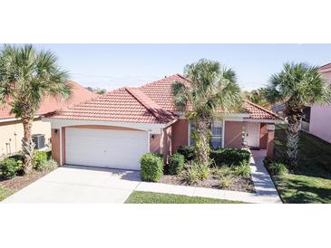 Charming single-story home with a red tile roof, tropical landscaping, and an attached two-car garage at 156 Carrera Ave, Davenport, FL 33897