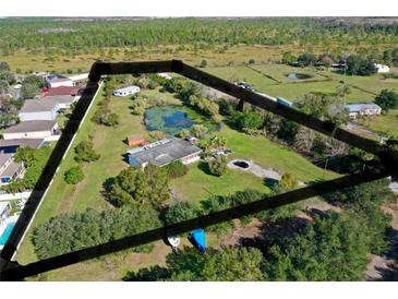 Expansive aerial view of a home with a private pond and lush greenery, highlighting the serene landscape at 4121 High Plains Ln, Kissimmee, FL 34744