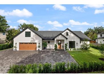 Stunning single-Gathering home with a manicured lawn, brick driveway and modern design under a beautiful blue sky at 5237 Haverill Dr, Orlando, FL 32809