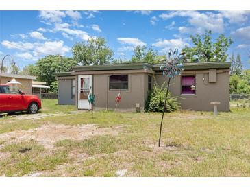 Single story home with a tan exterior and a red car parked in the front yard at 11509 Cameron St, Orlando, FL 32817