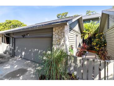 Attached garage featuring a stone accent wall and lush landscaping at 140 Deer Lake Cir, Ormond Beach, FL 32174