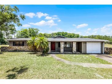 Charming single-story home with stone accents, a red front door and a well manicured lawn at 1508 Lake Mills Rd, Chuluota, FL 32766