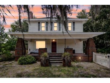 Charming two-story home with a brick porch and a neatly landscaped yard at sunset at 2418 W 1St St, Sanford, FL 32771