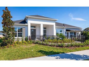 Charming home featuring a manicured lawn, dark roof, a black metal fence, and white columns at 2739 Ravencliffe Ter, Oviedo, FL 32765