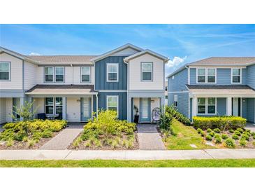 Charming townhouse with blue and white exterior and landscaped front yard on a sunny day at 14250 Sapelo Beach Dr, Orlando, FL 32827