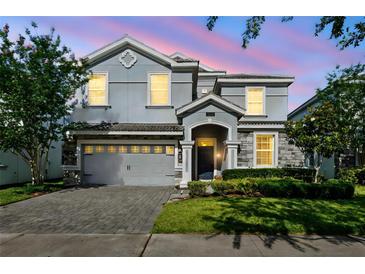 Charming two-story home showcasing lush landscaping and a paver driveway at 1520 Mulligan Blvd, Davenport, FL 33896