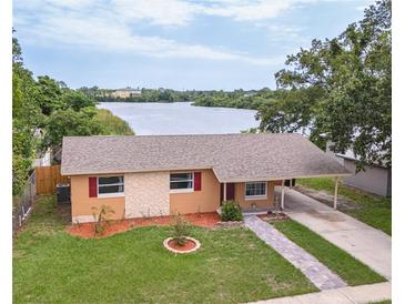Inviting waterfront home featuring a well-maintained lawn and a convenient carport at 331 Greens End St, Orlando, FL 32810