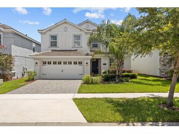 Two-story home featuring a manicured lawn, beautiful landscaping, and an attached two-car garage at 8822 Interlocking Ct, Davenport, FL 33896