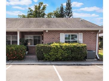 Charming brick condo featuring a well-maintained lawn and assigned parking spaces at 1230 Americana Pl, Orlando, FL 32807