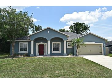 Charming blue home featuring a two-car garage, well-manicured lawn, and covered front entry way at 1947 Vienna Ave, Deltona, FL 32725