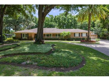 Stunning brick home featuring lush landscaping, mature trees, and a circular driveway at 2009 Woody Dr, Windermere, FL 34786
