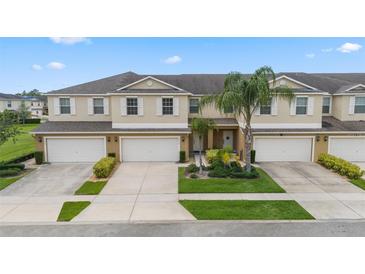 Beige two-story townhome featuring a well-maintained front yard, a driveway, and a one-car garage at 3018 Bargate St, Orlando, FL 32824